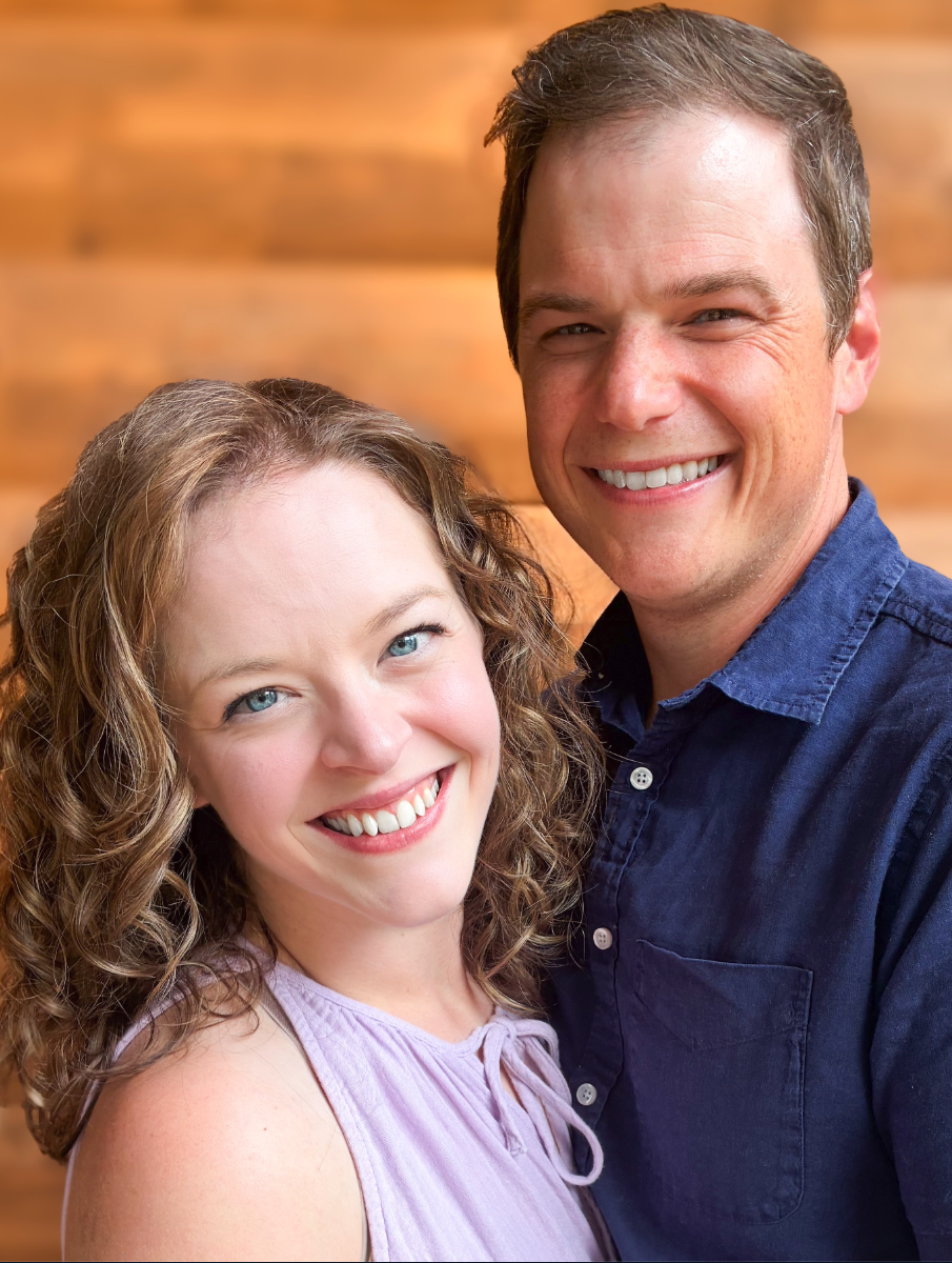 Brittany Martin smiling cheek to cheek with a man in a navy shirt against a wood wall
