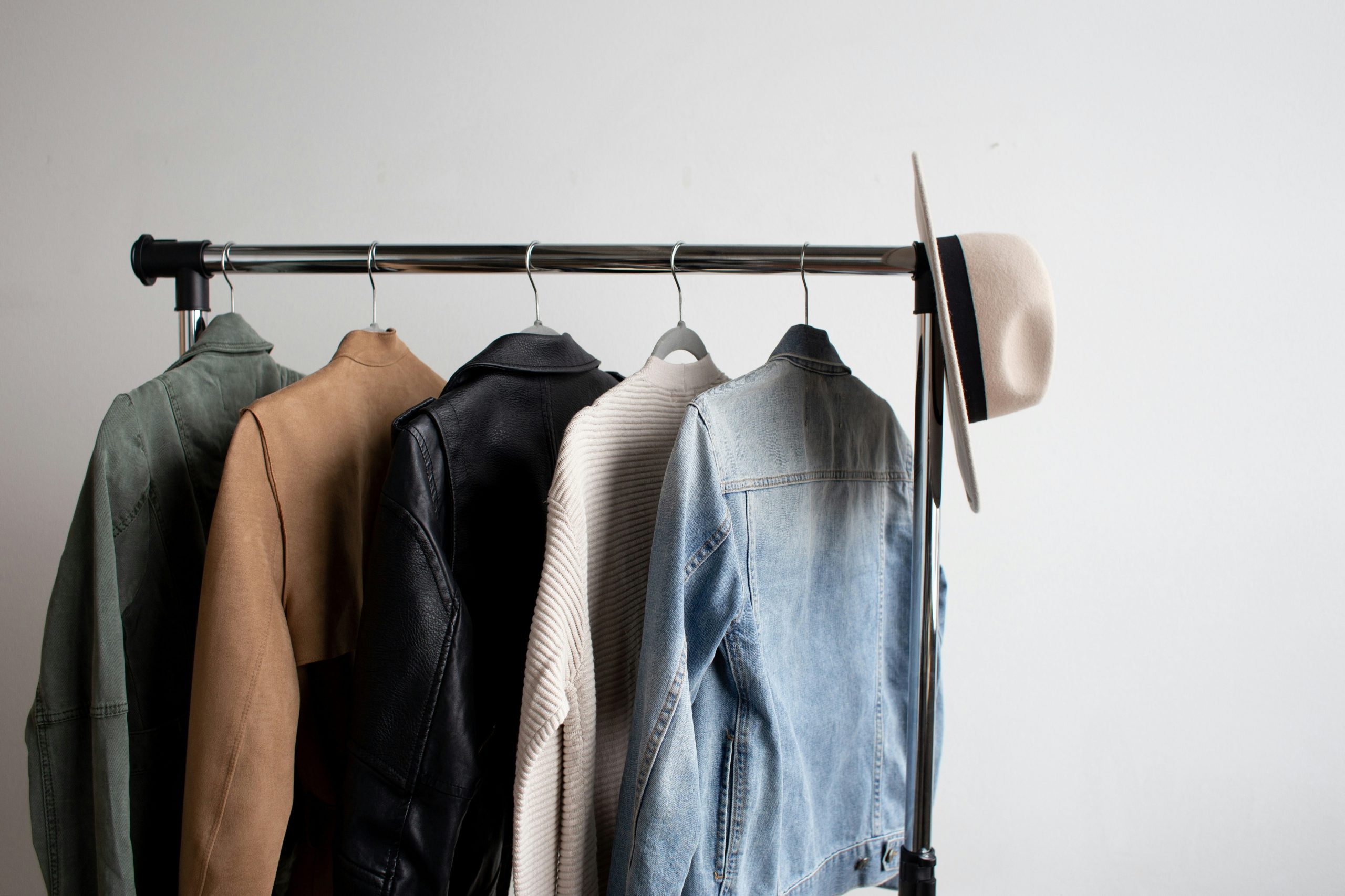 Jackets hanging on a clothing rack with a hat hung on the end
