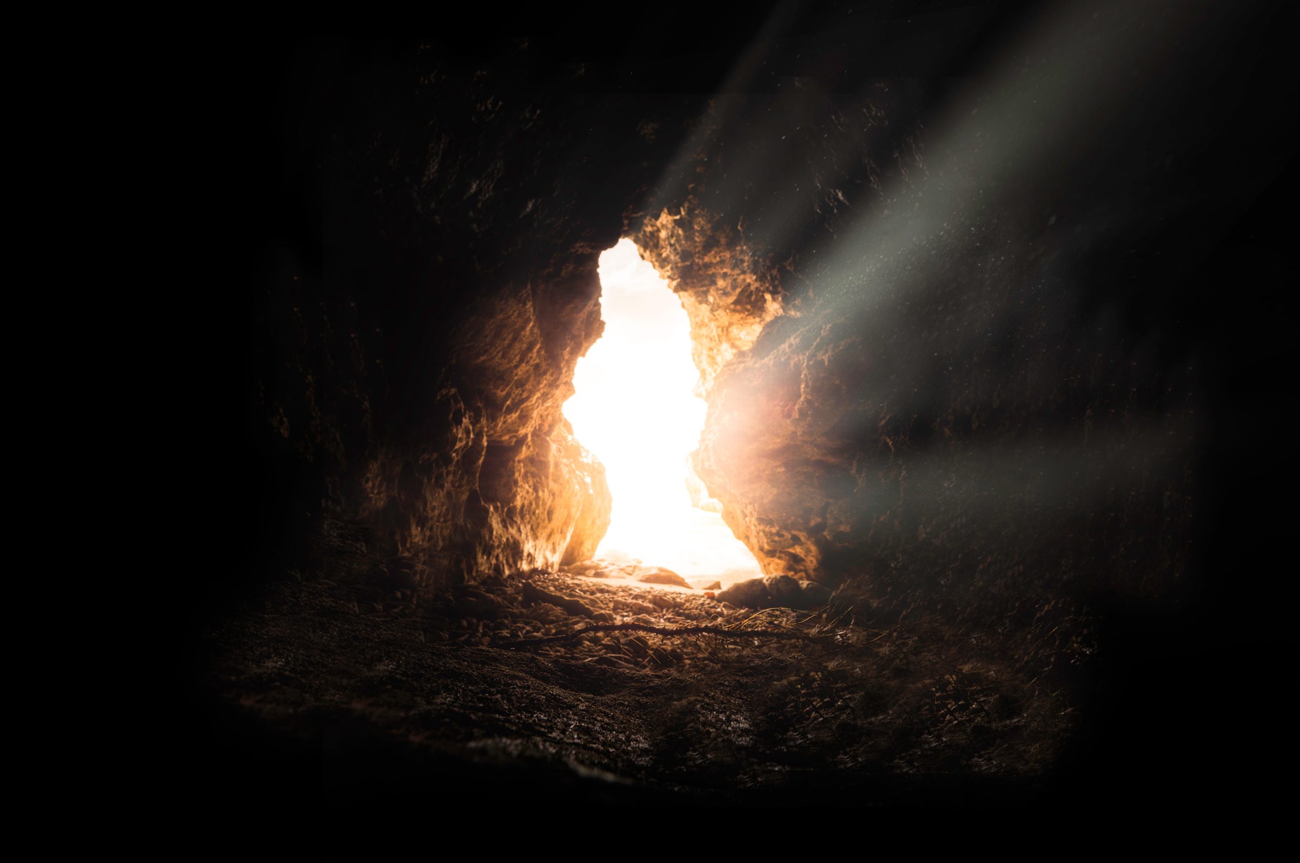 Light streaming into a dark cave through its opening, evoking the empty tomb