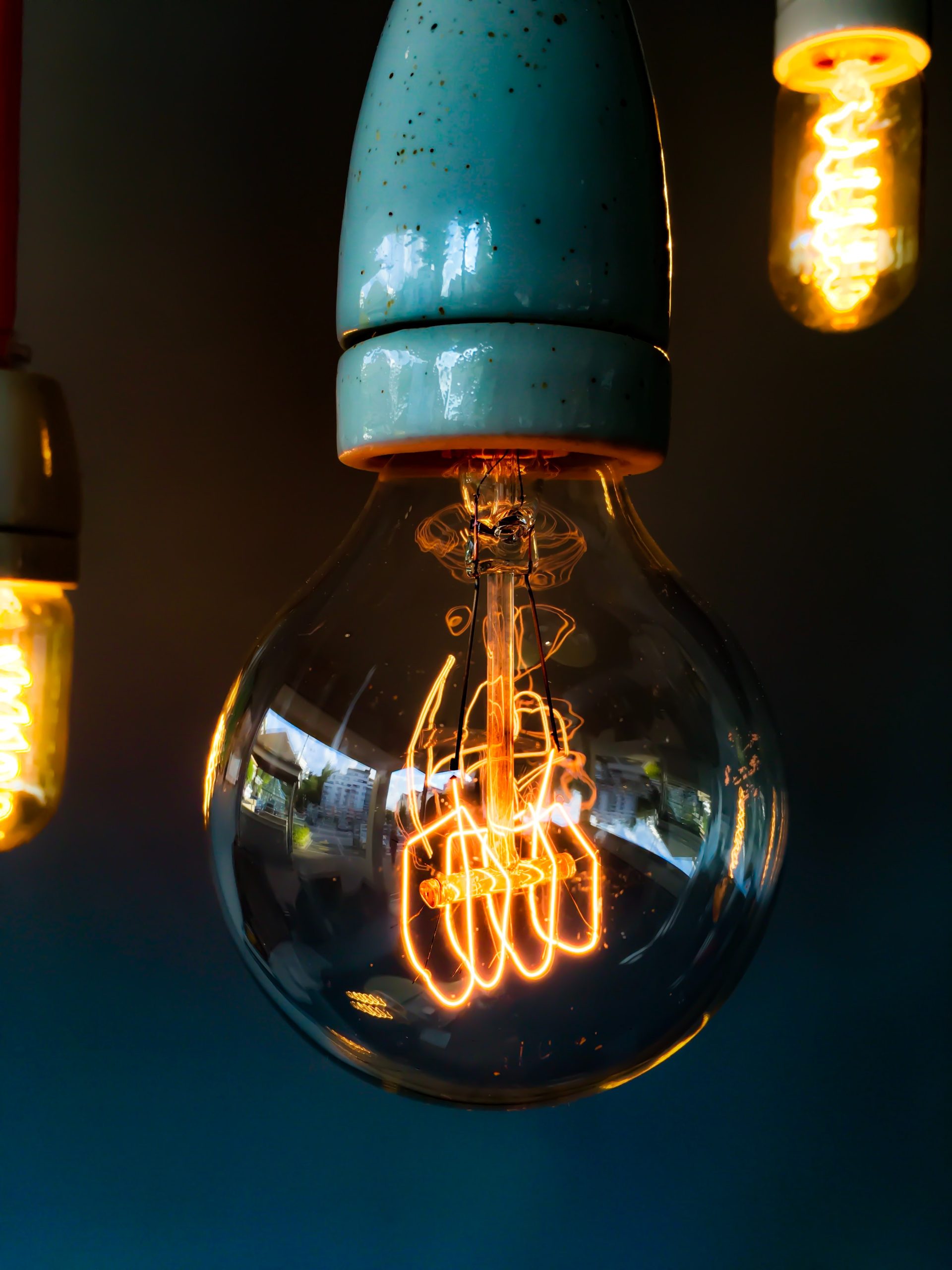 Glowing vintage filament light bulb hanging against a dark background