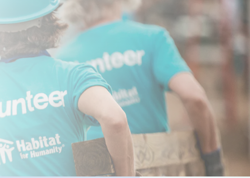 Habitat for Humanity volunteers in matching shirts carrying lumber