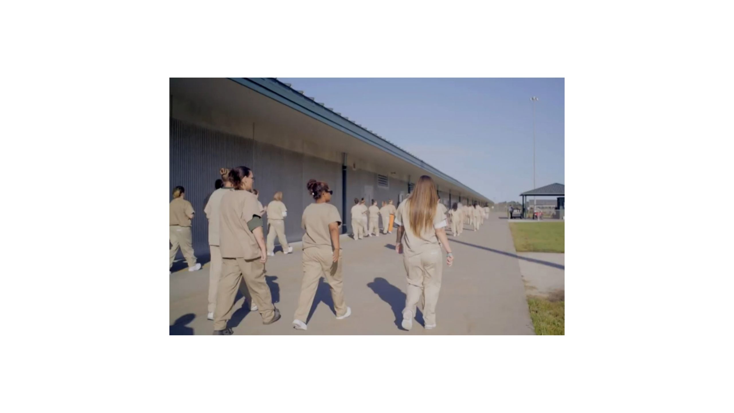 Women in prison uniforms walking in a correctional facility yard