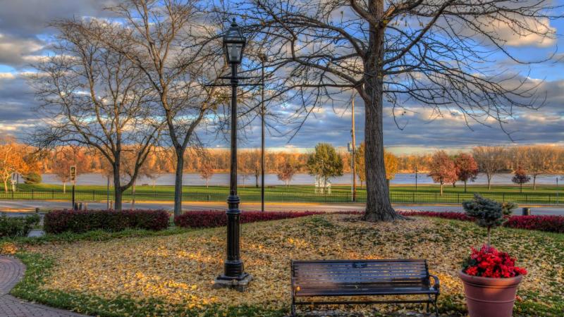Riverfront park in autumn with a lamppost, a bench and flowers along the Missouri River